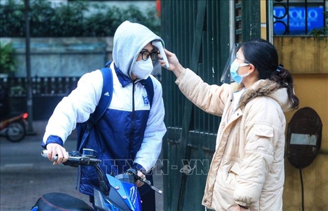 A 12th grader in Hà Nội's Phan Đình Phùng High school has his temperature checked before entering school. Hà Nội reopened schools to 12th graders on Monday after about seven months of closure due to the COVID-19 pandemic. 